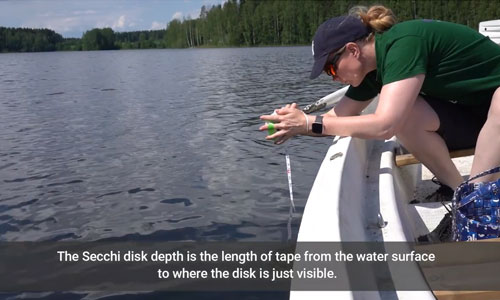 Scientist deploying mini-secchi disk on a small boat on a lake